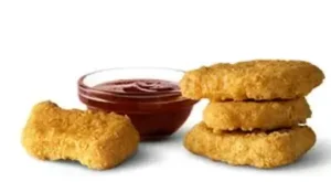 Four crispy Chicken McNuggets from McDonald's, served with dipping sauce