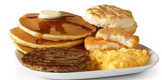 McDonald's Big Breakfast with Hotcakes featuring scrambled eggs, sausage patty, hash browns, biscuit, and fluffy hotcakes with syrup